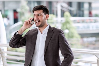 Mobil ofis kavramı. Yakışıklı başarılı beyaz iş adamı veya finansal arka planda bina ile onun cep telefonuyla konuşan Satılık adam. Açık ele alındığında, kentsel görünüyor efekti uygula.