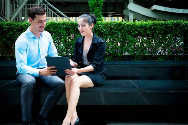 Genç iş liderleri kavramı. Genç işadamı işbirliği işçisi kadın açık City ile iş tartışıyor. Mavi gömlek ile Casual adam akıllı ve akıllıca ile not etmek aşağı konuşurken oturan kadın elbise.