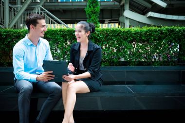 Genç iş liderleri kavramı. Genç işadamı işbirliği işçisi kadın açık City ile iş tartışıyor. Mavi gömlek ile Casual adam akıllı ve akıllıca ile not etmek aşağı konuşurken oturan kadın elbise.