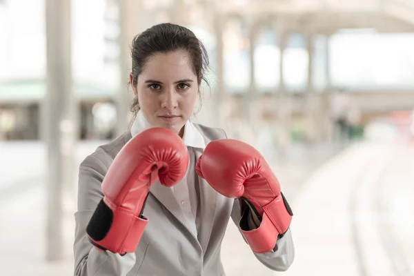 Businesswoman wearing red boxing gloves with guard posture ready