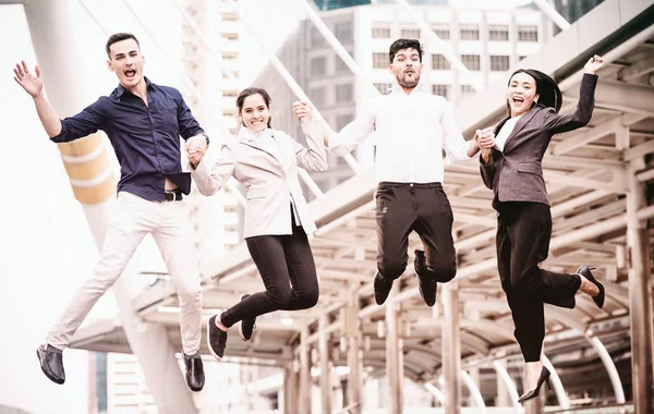 Young business team jumping for huge celebration of successful team work. Taken outdoor in afternoon with soft vintage effect. Multi race business team concepts.