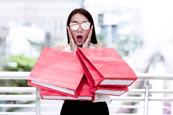 Retrato de jovem shopaholic mulher com muitos sacos de compras vermelhos . — Fotografia de Stock