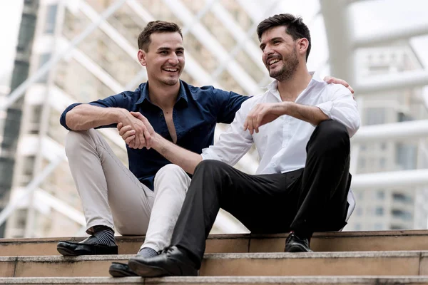 Два счастливых бизнесмена садятся на бетонную лестницу и трясутся. — стоковое фото