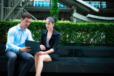 Genç iş liderleri kavramı. Genç işadamı işbirliği işçisi kadın açık City ile iş tartışıyor. Mavi gömlek ile Casual adam akıllı ve akıllıca ile not etmek aşağı konuşurken oturan kadın elbise.