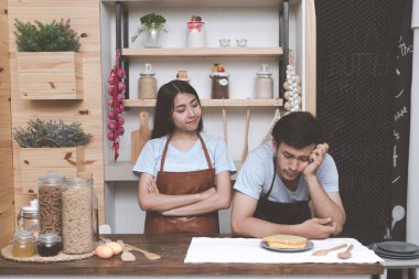 Genç Beyaz adam mutfakta Çinli kız arkadaşıyla yemek pişirmek için ne hakkında düşünmeye çalışıyorum. Marrige kavramı önce birlikte yaşayan genç Çift.