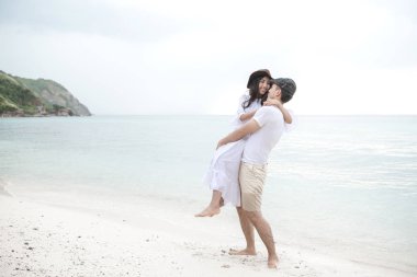 Birbirimizi kumsalda tutan bir çift. Birbirimizi tutan sahilde genç mutlu ırklararası çift. Asyalı kadın, beyaz adam. Genç karışık yarış romantizm kavramı.