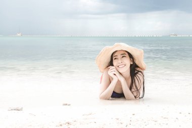 Kumsalda eğleniyor güzel genç tek Çinli kadın. mutlu bırakmasını rahatlatıcı, giyen bikini, plaj şapka.