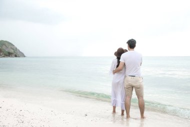 Birbirimizi kumsalda tutan bir çift. Birbirimizi tutan sahilde genç mutlu ırklararası çift. Asyalı kadın, beyaz adam. Genç karışık yarış romantizm kavramı.