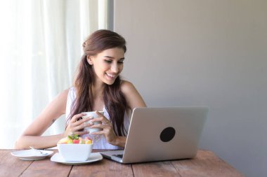 Kahve içer ve dışında çalışan kadın. Dizüstü bilgisayarda onu tatil sırasında bir tropikal çalışan. Beyaz beyaz elbise ile kadın. Çevik. modile ofis kavramı.