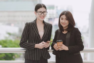 Kahve Mola mola sırasında iki güzel kendine güvenen Asya iş kadını. İki kadın ofiste uygun office mola sırasında doğal ışık açık alınan konuşuyor. Kadın kariyer kavramı.