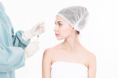 Profesyonel plastik cerrahi hizmetleri. Güzel beyaz kadın yaklaşık botox ile genç kadın Çinli doktor tarafından enjekte edilebilir yüze portresi. Beyaz izole.