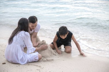 Genç aile Plajı kum kale. Plaj oynamaya genç mutlu Interracial aile kum. Asyalı kadın, beyaz adam, genç çocuk. Genç karışık yarış aile kavramı.