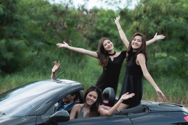 Playboy parti kavramı. Dört güzel Asyalı kadınlar kaygısız bir partiye giderken bir özgürlük poz yapmak ile Cabrio spor arabanın içinden genç beyaz erkek.
