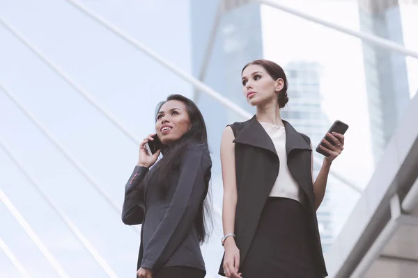 Dos hermosas mujeres de negocios seguras hablando por teléfono juntas — Foto de Stock