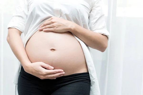 健康的中国母性观念 年轻的中国孕妇的肖像在她的家和抚摸她的肚子 采取室内与真正的六月大孕妇 — 图库照片