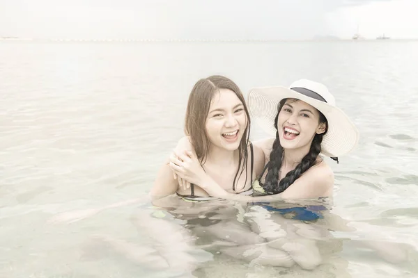 Group of beautiful young single chinese women having fun on beach. Playing with water, wearing bikini, beach hat.