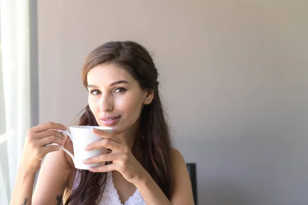 Woman having coffee and smile. Beautiful white woman having her morning coffee and smile looking very happy.