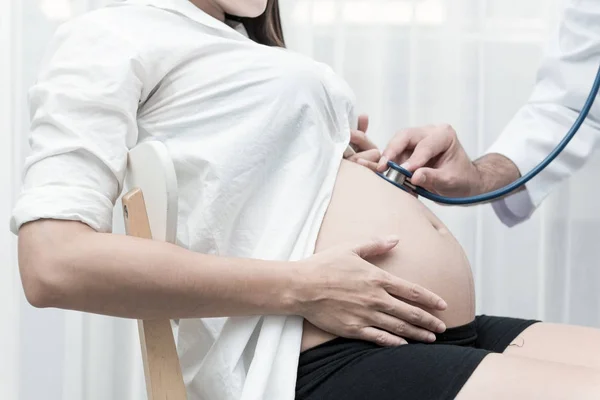 ハウス ドクターのコンセプトです 白医師が彼女の妊娠の進歩をクイック チェックのため自宅で妊娠中のアジア中国の女性を訪問します ヶ月妊婦で屋内撮影 — ストック写真