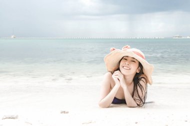 Kumsalda eğleniyor güzel genç tek Çinli kadın. mutlu bırakmasını rahatlatıcı, giyen bikini, plaj şapka.