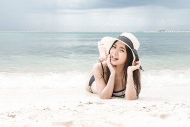 Kumsalda eğleniyor güzel genç tek Çinli kadın. mutlu bırakmasını rahatlatıcı, giyen bikini, plaj şapka.