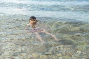 Plaj portre üzerinde genç Çinli çocuk. Genç çocuk sahilde okyanusta veriyorsun. Çinli Asyalı çocuk, tabaklanmış deri.