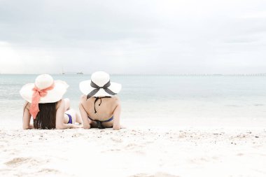 Kumsalda eğleniyor güzel genç tek Çinli kadın. Rahatlatıcı, bikini, plaj şapka giyen oturarak.