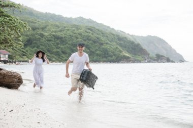 Plajda çalışan bir çift. Çalışan ve birbirlerini takip sahilde genç mutlu ırklararası çift. Asyalı kadın, beyaz adam. Genç karışık yarış romantizm kavramı.