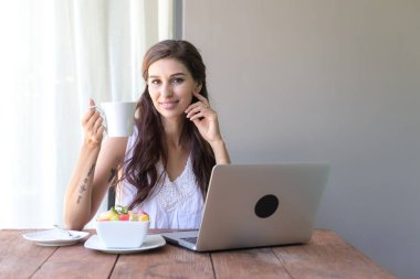 Kahve içer ve dışında çalışan kadın. Dizüstü bilgisayarda onu tatil sırasında bir tropikal çalışan. Beyaz beyaz elbise ile kadın. Çevik. modile ofis kavramı.