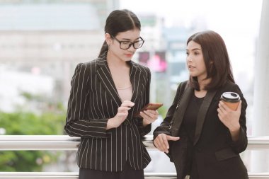 Kahve Mola mola sırasında iki güzel kendine güvenen Asya iş kadını. İki kadın ofiste uygun office mola sırasında doğal ışık açık alınan konuşuyor. Kadın kariyer kavramı.