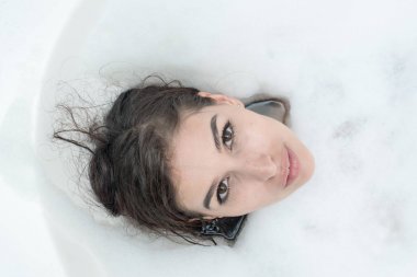 Güzel genç beyaz kadın zevk köpük banyosu rahatlatıcı. Dinlenme, göz, gülümseyen açın. Beyaz beyaz kadın. Üstten Görünüm