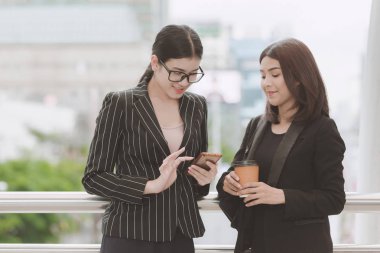 Kahve Mola mola sırasında iki güzel kendine güvenen Asya iş kadını. İki kadın ofiste uygun office mola sırasında doğal ışık açık alınan konuşuyor. Kadın kariyer kavramı.