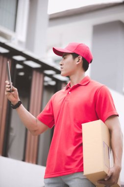 Genç lojistik kariyer kavramı. Onun tableti müşteri ev konumda arayan mutlu teslimat adam. Onun erken yirmili kırmızı polo gömlekli adam Asya Çin uygun.