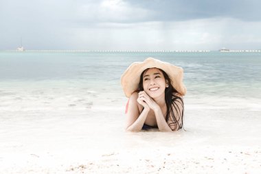 Kumsalda eğleniyor güzel genç tek Çinli kadın. mutlu bırakmasını rahatlatıcı, giyen bikini, plaj şapka.