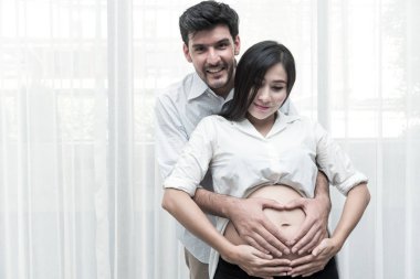 Karışık yarış ebeveynlik kavramı. Genç Çince hamile ve her diğer holding beyaz erkek kocası portresi. Gerçek altı aylık hamile kadın ile kapalı alınan.