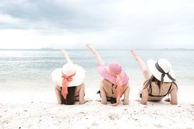 Kumsalda eğleniyor güzel genç tek Çinli kadın. Rahatlatıcı, bikini, plaj şapka giyen oturarak.
