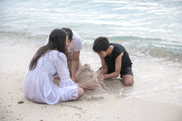 Genç aile Plajı kum kale. Plaj oynamaya genç mutlu Interracial aile kum. Asyalı kadın, beyaz adam, genç çocuk. Genç karışık yarış aile kavramı.