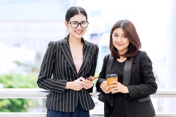 Two beautiful confident asian business woman taking a coffee bre