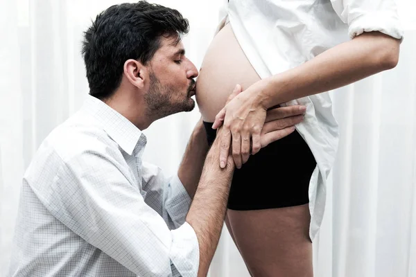 混合种族父母的概念 年轻的中国人怀孕的画像与她的白人男性丈夫亲吻她的肚子与喜悦 采取室内与真正的六月大孕妇 — 图库照片