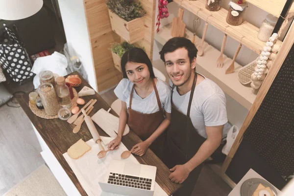 Young white man in kitchen with his chinese girlfriend looking to camera. Young couple living together before marrige concept.