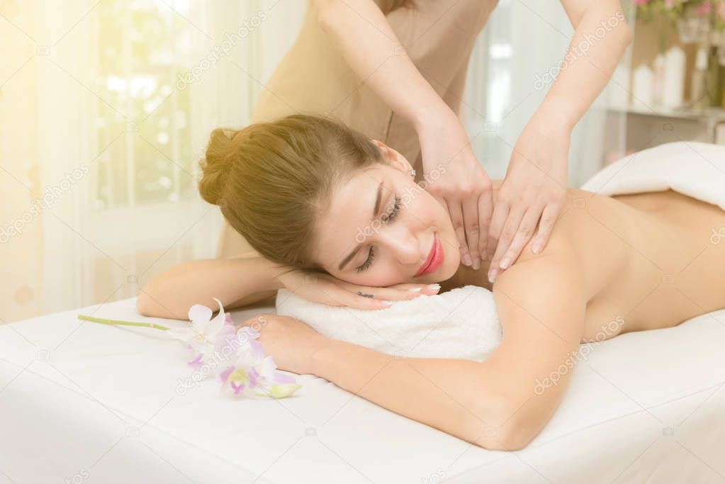 Asian exotic holiday spa concept. Beautiful young white woman enjoy relaxing during massage at spa, taken indoor in real spa location.