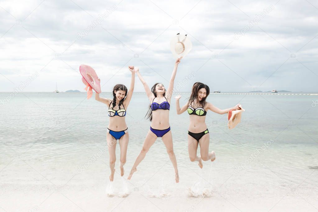 Beautiful young single chinese women having fun on beach. Jumping, wearing bikini, beach hat.