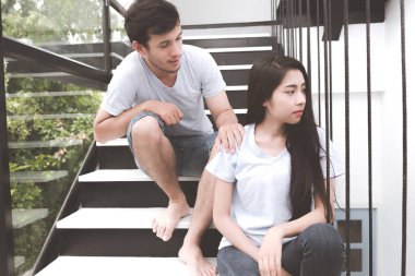 Karışık yarış severler kavramı. Beyaz genç erkek genç ve güzel Çinli kız arkadaşıyla bir merdivende savunarak. Giyiyor mavi jeans, mavi gömlek ve erken yirmili. Kapalı alınan.