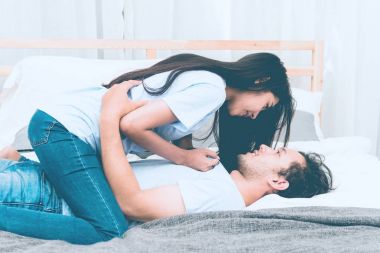 Karışık yarış severler kavramı. Genç ve güzel Çinli kız arkadaşıyla samimi getting onun yatak odasında genç beyaz erkek. Giyiyor mavi jeans, mavi gömlek ve erken yirmili. Kapalı alınan.