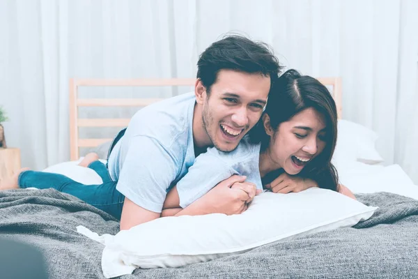 Mixed race lovers concept. Young white male in his bedroom getting intimate with his pretty young chinese girlfriend. Wearing blue jeans, blue shirt and in their early twenties. Taken indoor.