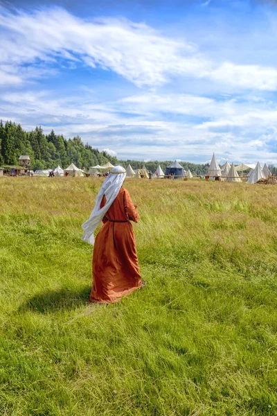 Ortaçağ giysili bir kadına bir çim üzerinde gider