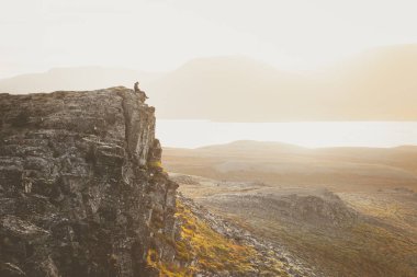 Fiyatı bir kayalık uçurum gün batımı sırasında üzerinde. Harika atmosfer 