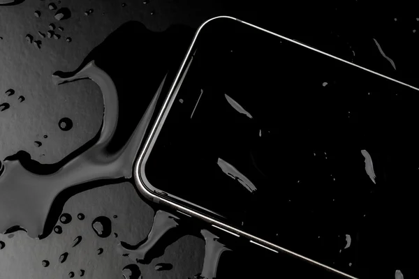 Водонепроницаемый смартфон с брызгами воды на черном фоне — стоковое фото