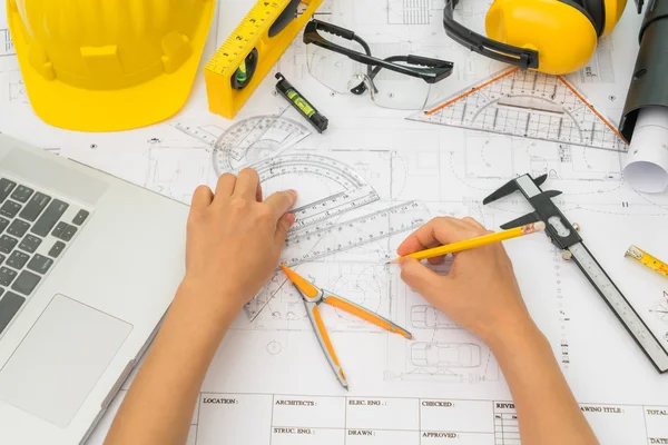 Lämna över byggnadsplanerna med gul hjälm och ritverktyg — Stockfoto