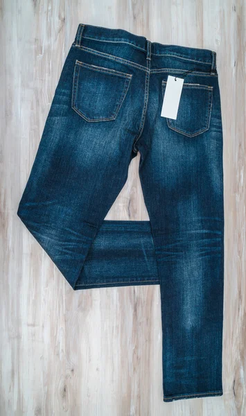 Calça jeans azul com preço no fundo de madeira  . — Fotografia de Stock