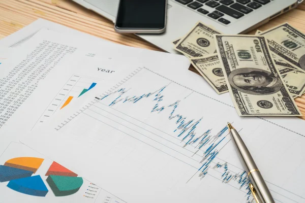 Financial charts on the table with laptop , phone ,dollars bankn — Stock Photo, Image